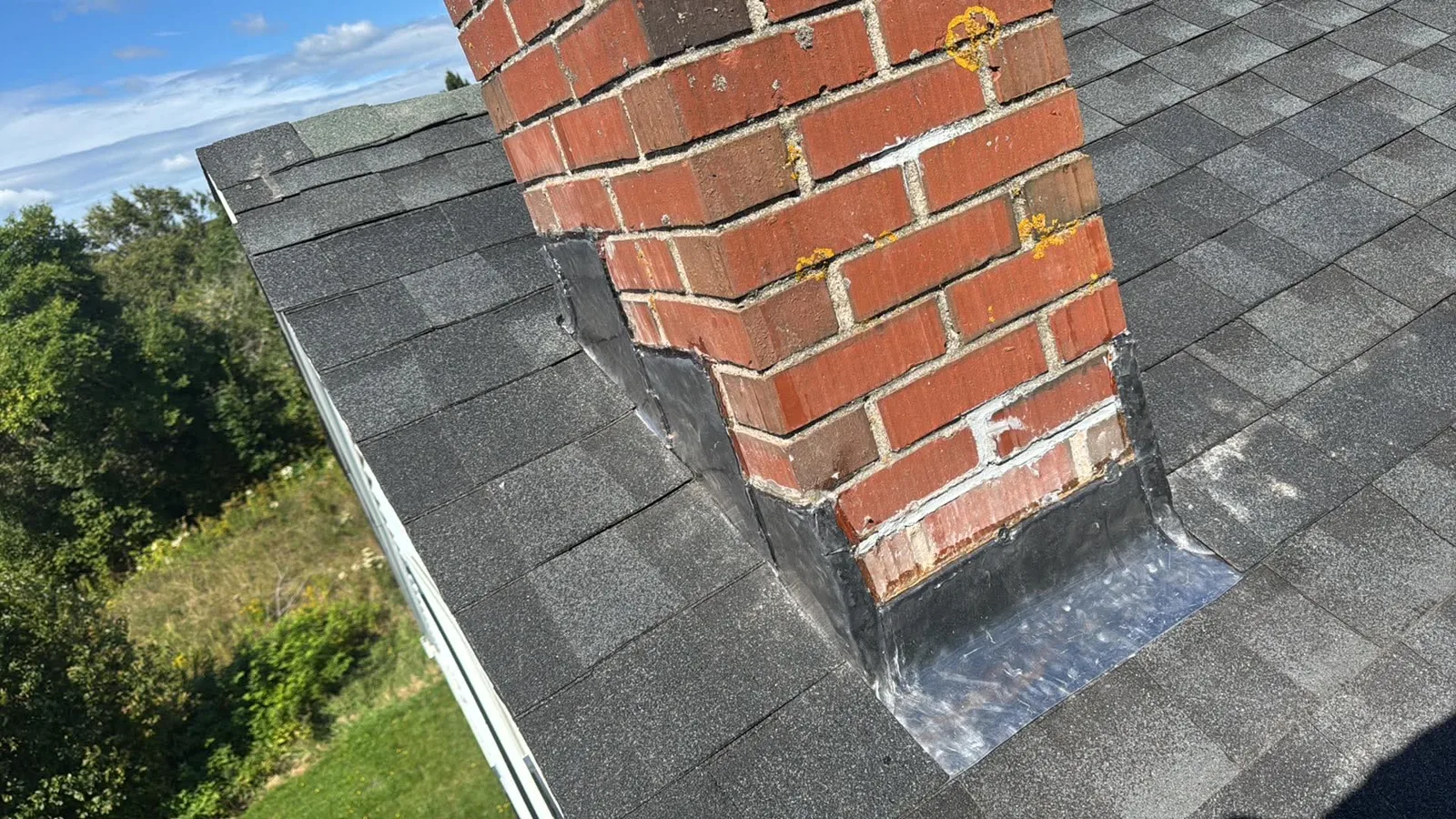 Step and apron flashing around a brick chimney on a shingle roof