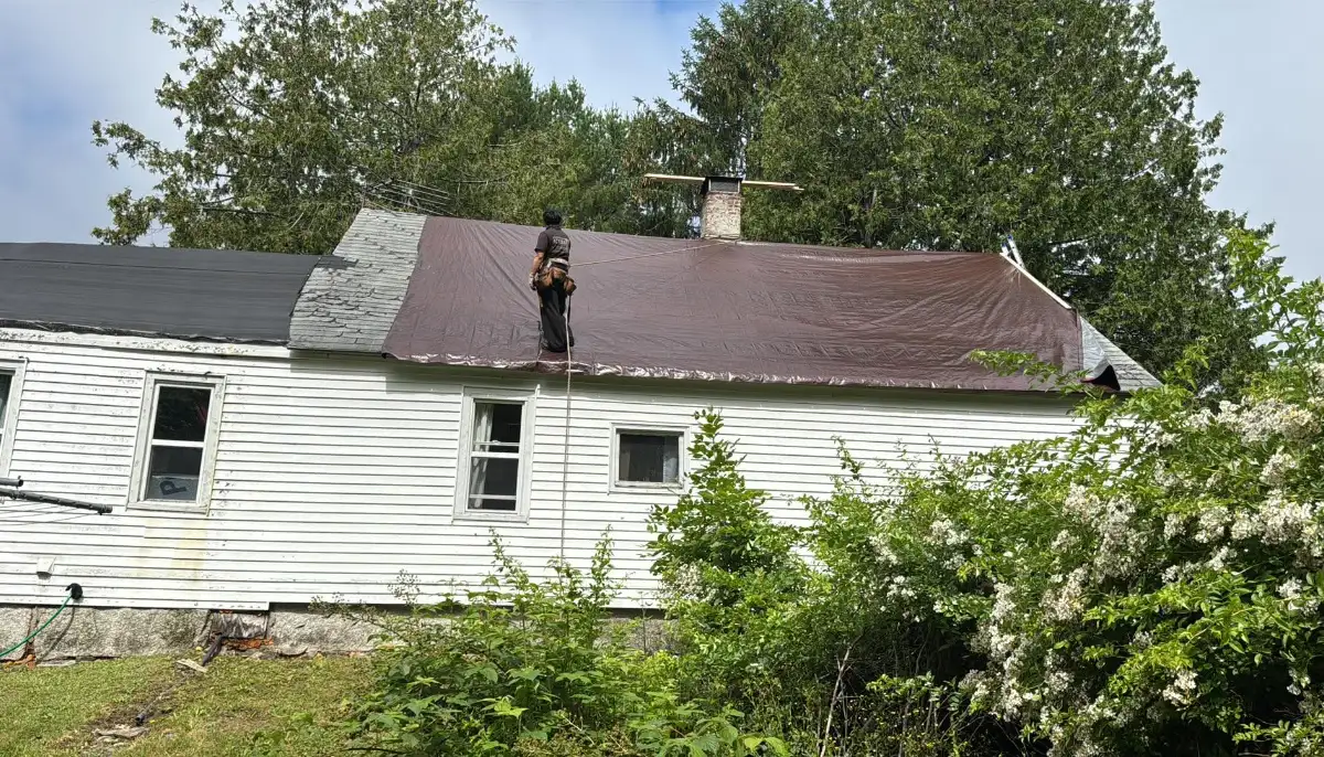 Roofer installing an emergency tarp on a storm-damaged roof