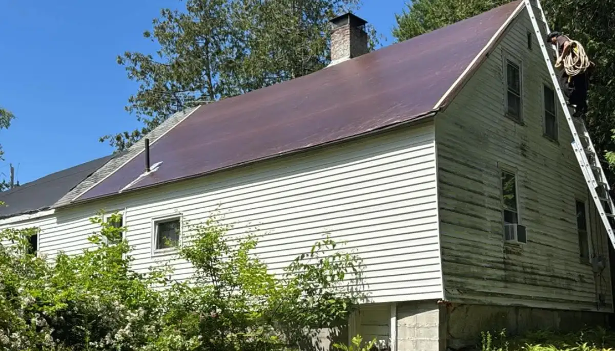 Emergency tarp secured over a damaged roof, roofer on ladder